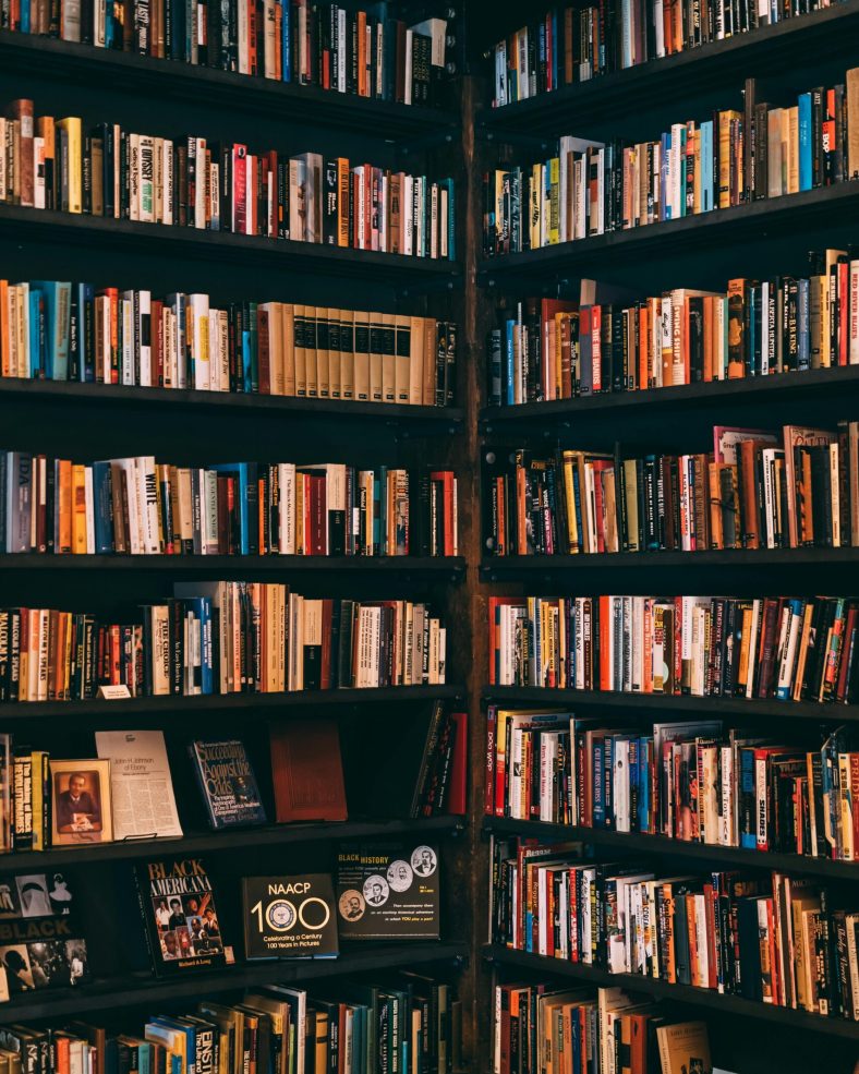 Corner view of a library with dark wooden bookshelves filled with a variety of books.